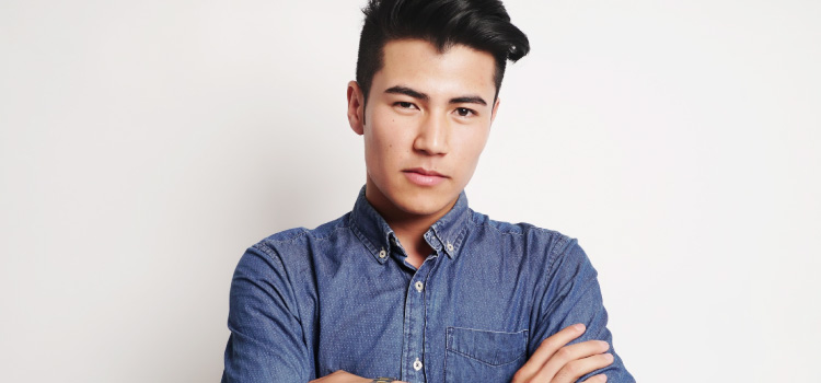 young man with black hair and denim button up, arms crossed