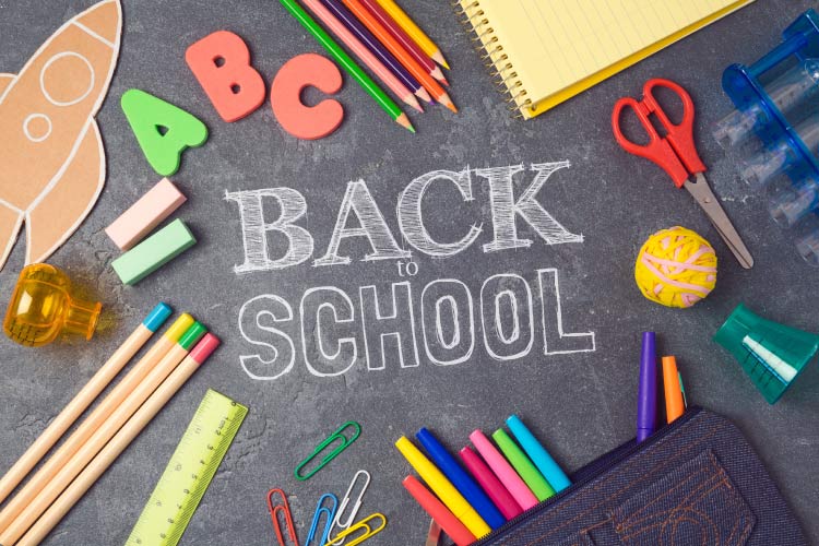 Aerial view of black chalkboard with the words BACK TO SCHOOL surrounded by various colorful school supplies