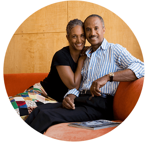 husband and wife cuddling on couch smiling