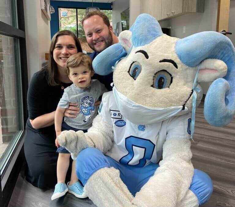 Dr. Zukerman and his family smile with the UNC mascot, Rameses, at CarolinasDentist in Chapel Hill