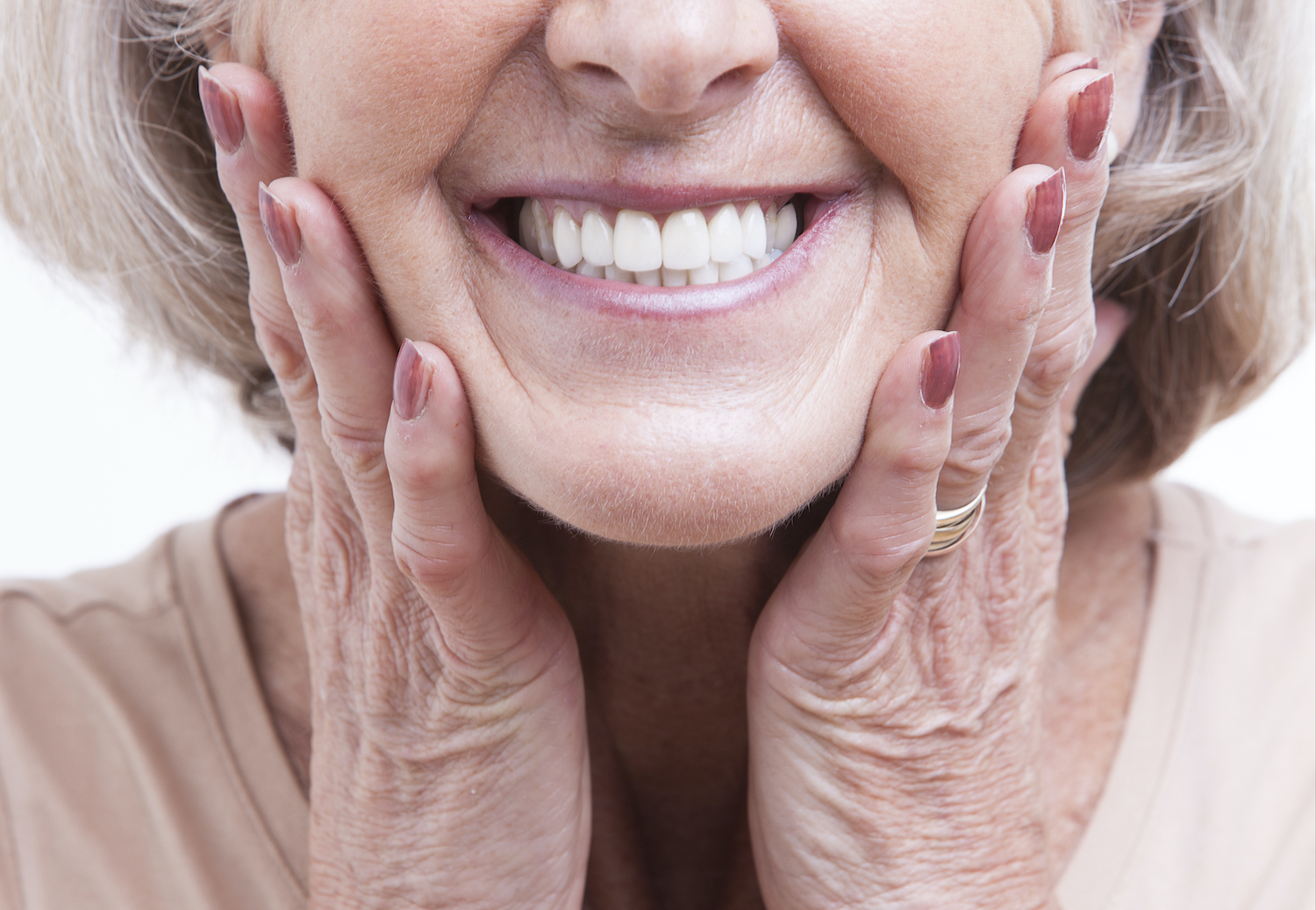 Closeup of the lower half of a woman's face as she smiles and touches her cheeks