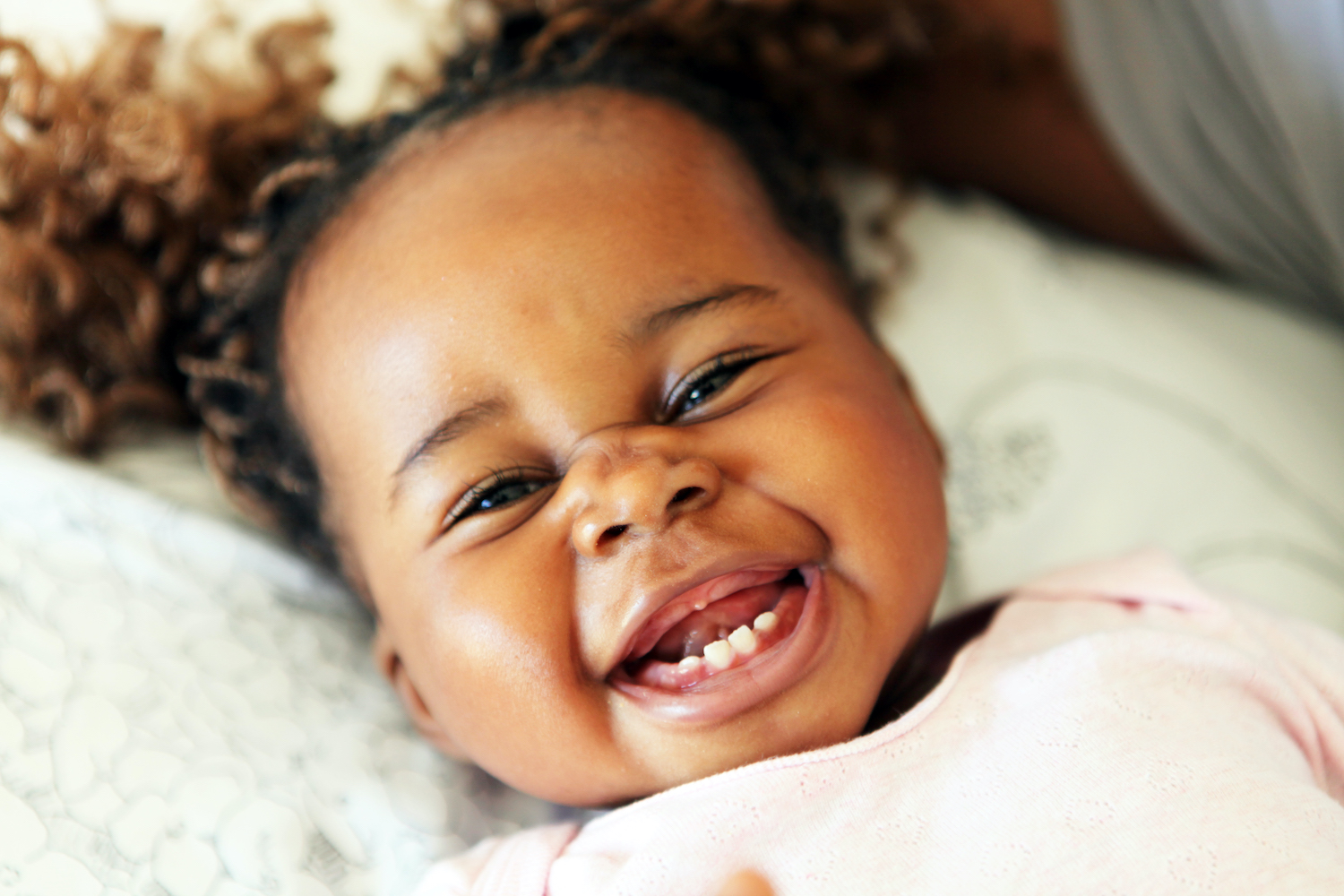 Closeup of a young baby smiling with her bottom baby teeth