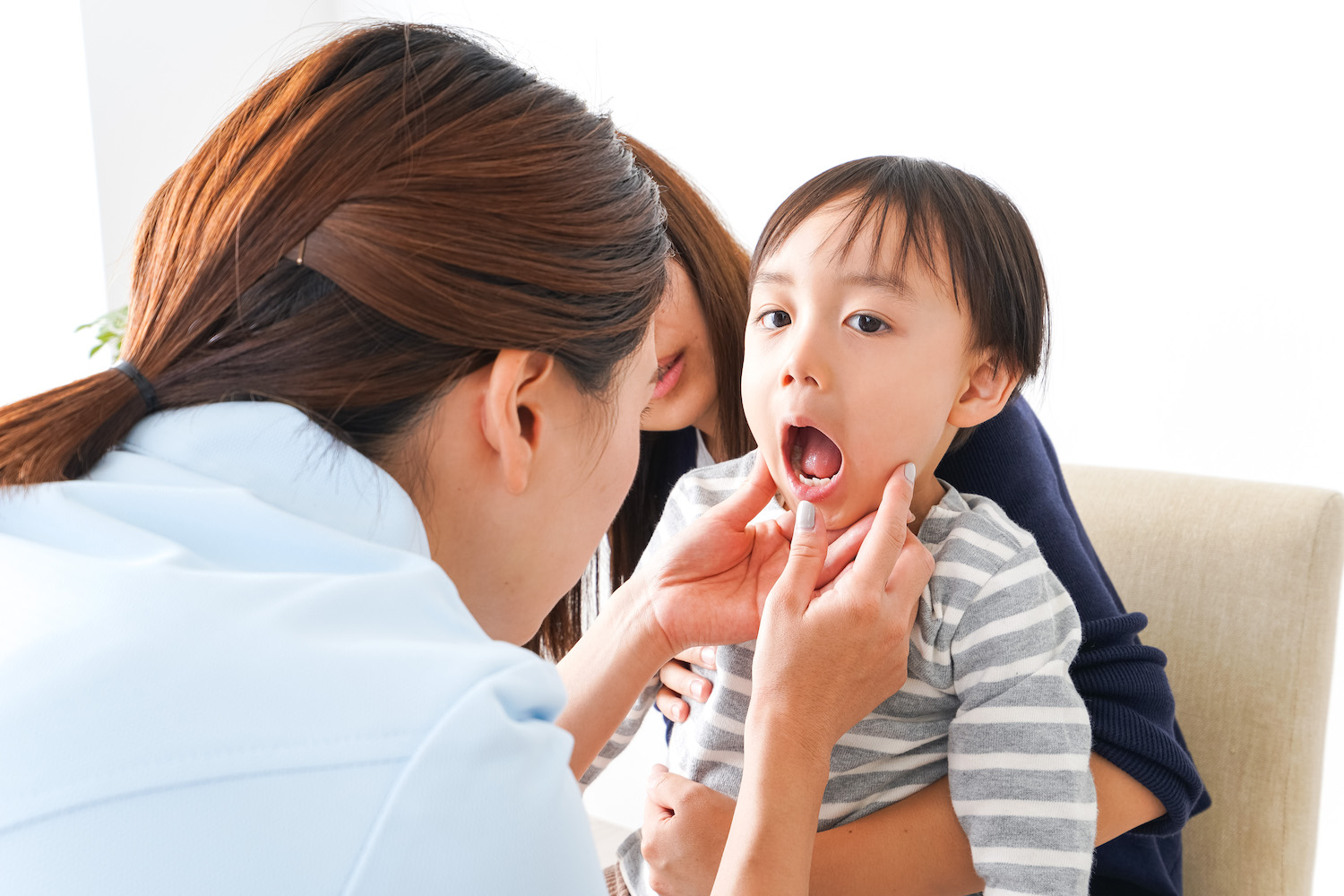 Children's dentist looks into a child's mouth at sealants after applying a fluoride treatment