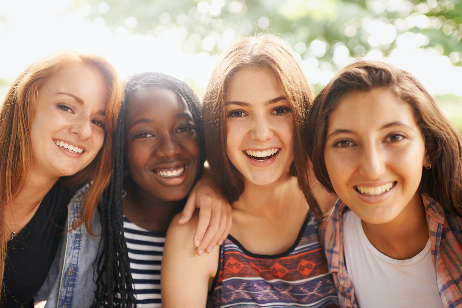 A group of 4 young teenage girls smile while outside