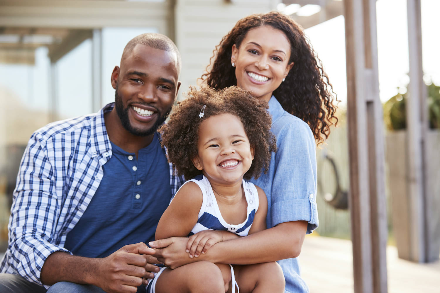 A Black mom and dad smile with their adorable daughter before visiting their family dentist at CarolinasDentist