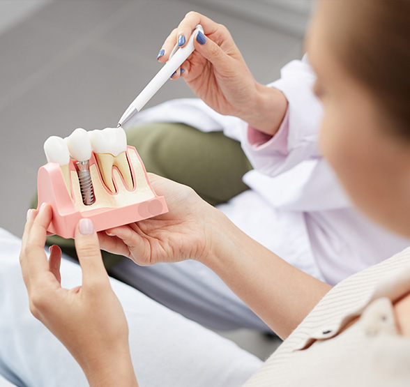 Photograph of dental provider explaining benefits of dental implants to patient to restore missing teeth.