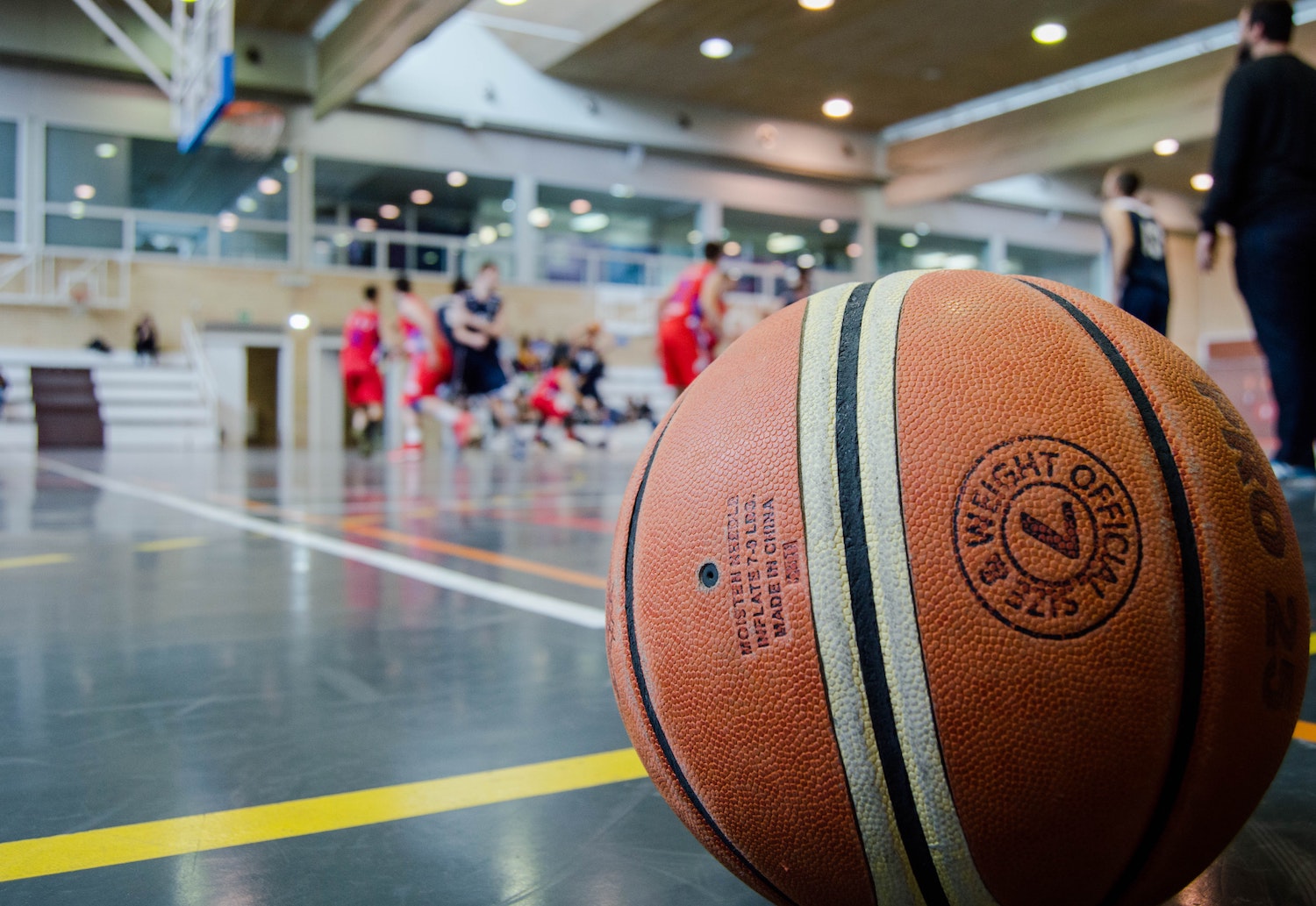 A basketball sits on a court in front of players playing basketball