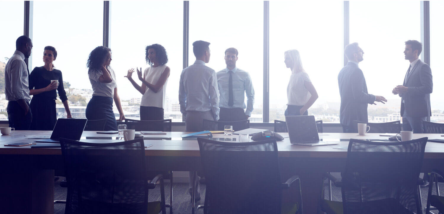 Group of men and women in business chatting about their career by a conference table